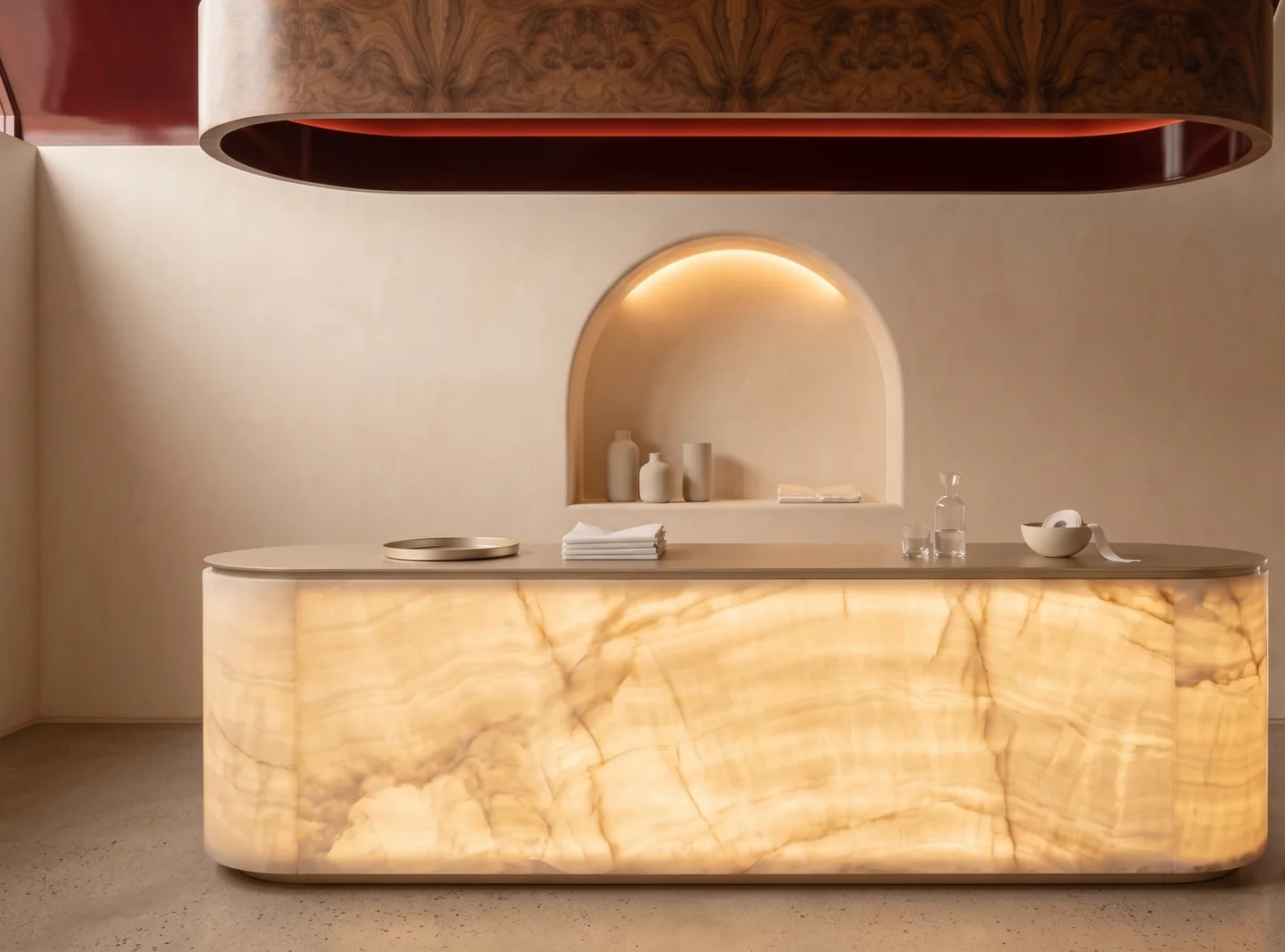 Visualisation of a shop counter: a backlit onyx front with rounded ends and a stone top, an arched niche lit from above, and a timber ceiling raft overhead.