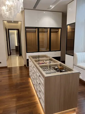 Umm Suqeim villa: Dressing room with a glass-topped island and lit shelving